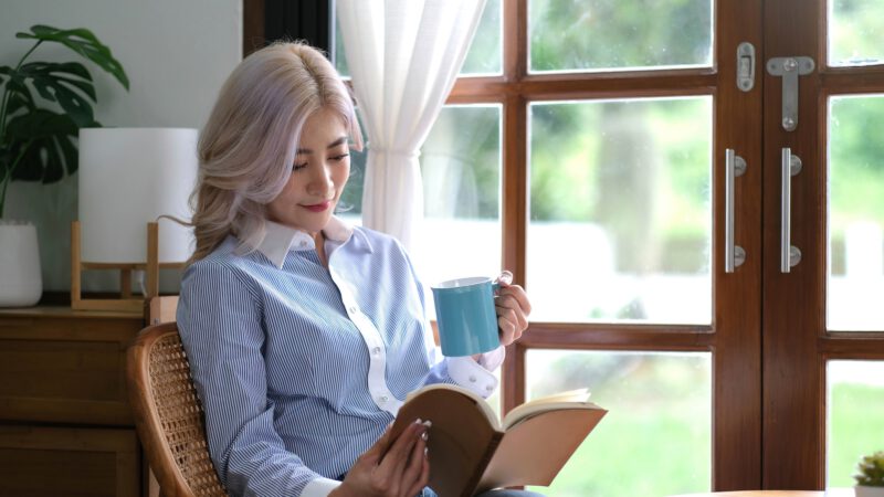 Portrait Asian woman reading book and relaxing with coffee at home